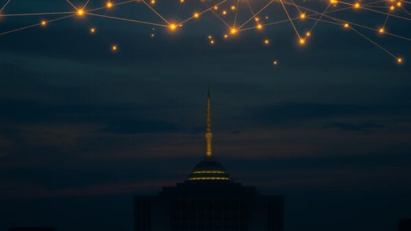 United Nations headquarters silhouette at dusk with glowing network nodes floating above, interconnected golden light streams across dark sky, diplomatic blue and gold color scheme, cinematic editorial photography, no text no letters no words no writing no signs no labels no watermarks no logos no typography no numbers on surfaces