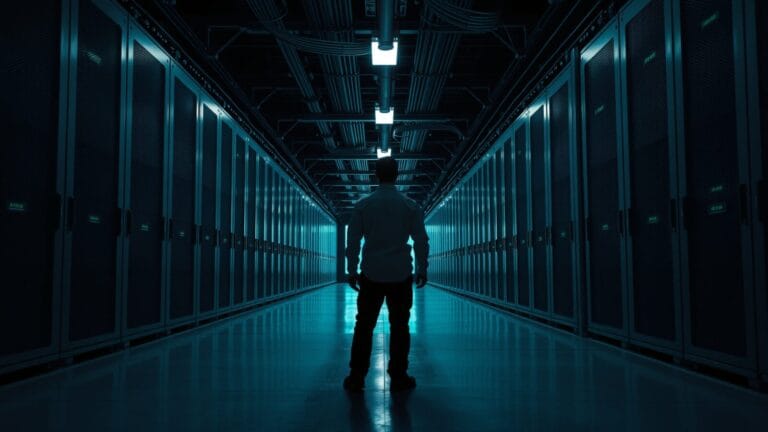 SubQ : 12 millions de tokens pour 8 dollars, vraiment ? 7 Allée d'une salle des machines déserte, racks d'acier dans une lumière vert-bleu, technicien de dos au loin.