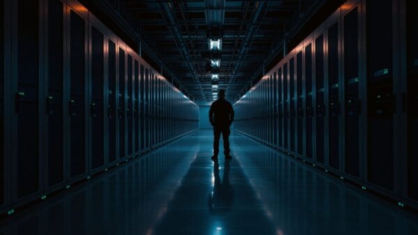 Silhouette d'un technicien de dos dans une salle de serveurs institutionnelle au crépuscule.